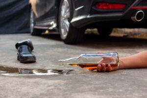 A liquor bottle dropped on the floor with a car and shoe in the background—don’t drink and drive.