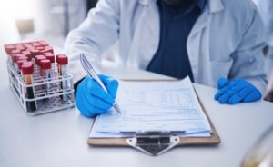 Blood test, scientific documents, and hands in a laboratory setting, focusing on healthcare results, research, or review.