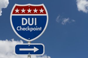 A red, white, and blue American highway road sign with the words "DUI Checkpoint" prominently displayed, set against a clear sky background.