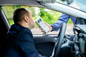 Driver being tested for alcohol content using a breathalyzer.